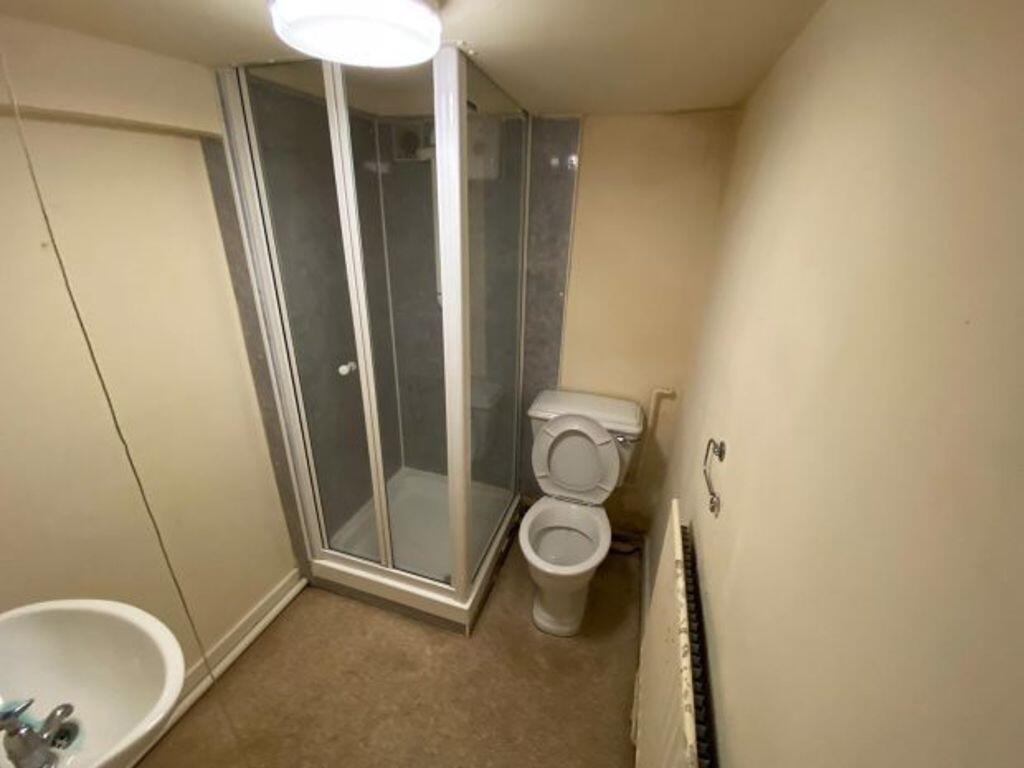 A compact bathroom featuring a corner shower en...