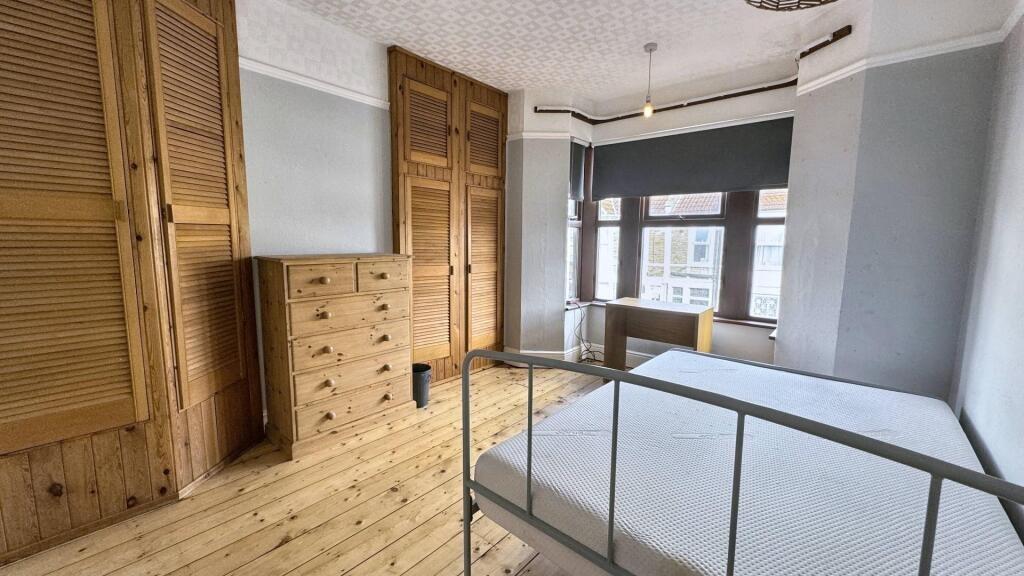 Bright double bedroom featuring natural wood fl...