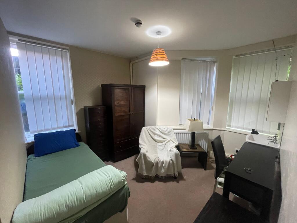 A cozy living space featuring a single bed, woo...