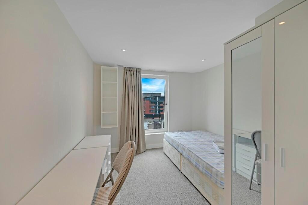 A bright, neatly arranged single bedroom featur...