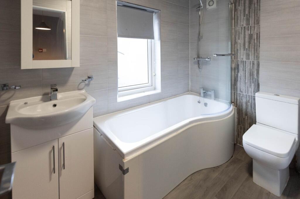 Modern bathroom featuring a white bathtub, a co...