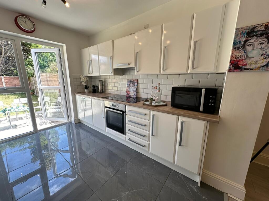 A modern kitchen featuring sleek white cabinets...