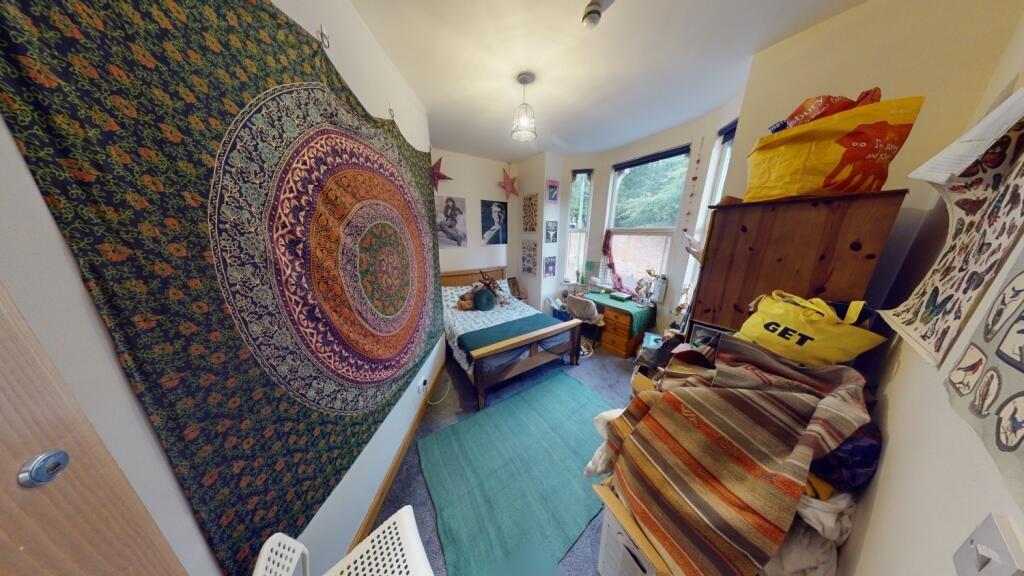 A cozy single bedroom with vibrant wall tapestr...