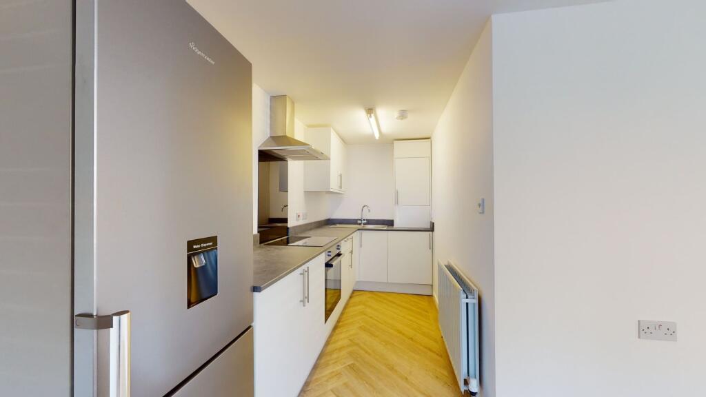A modern, clean kitchen featuring white cabinet...