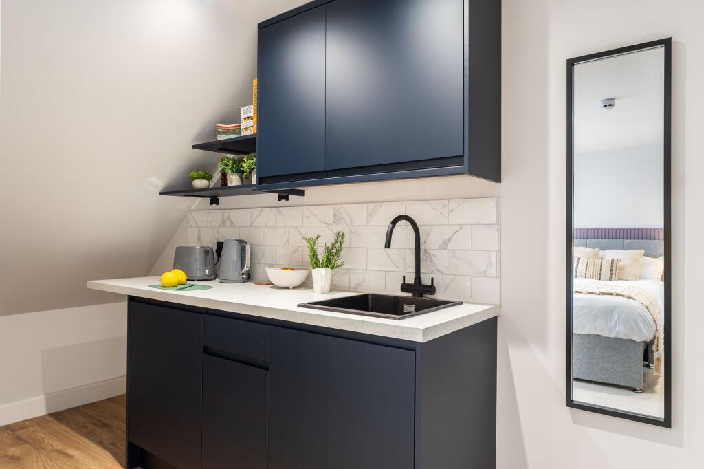 Modern kitchen with sleek navy cabinetry, a whi...