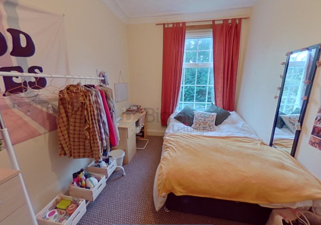 Cozy single bedroom featuring a large window wi...