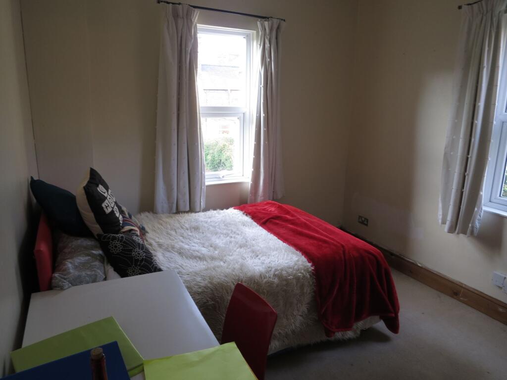 A cozy bedroom featuring a double bed adorned w...