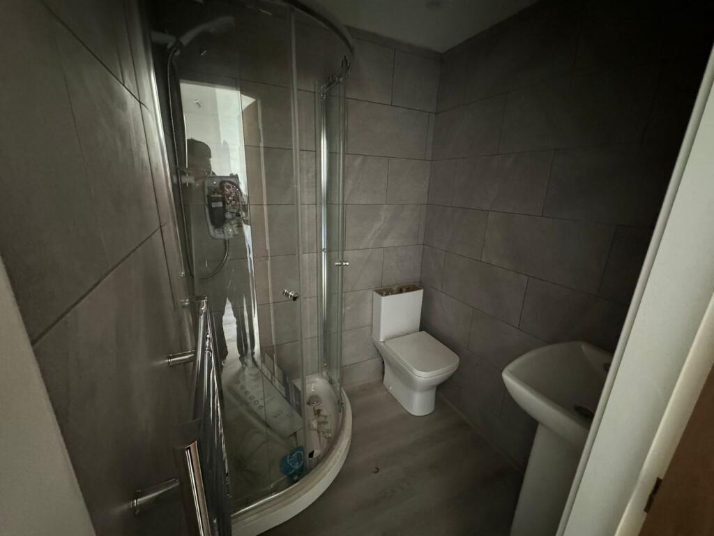 A modern bathroom featuring a curved glass show...
