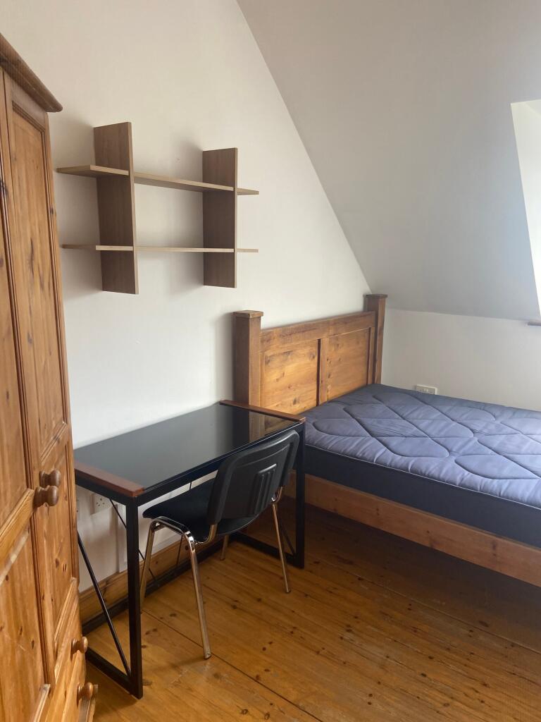 A cozy double bedroom featuring a wooden bed fr...