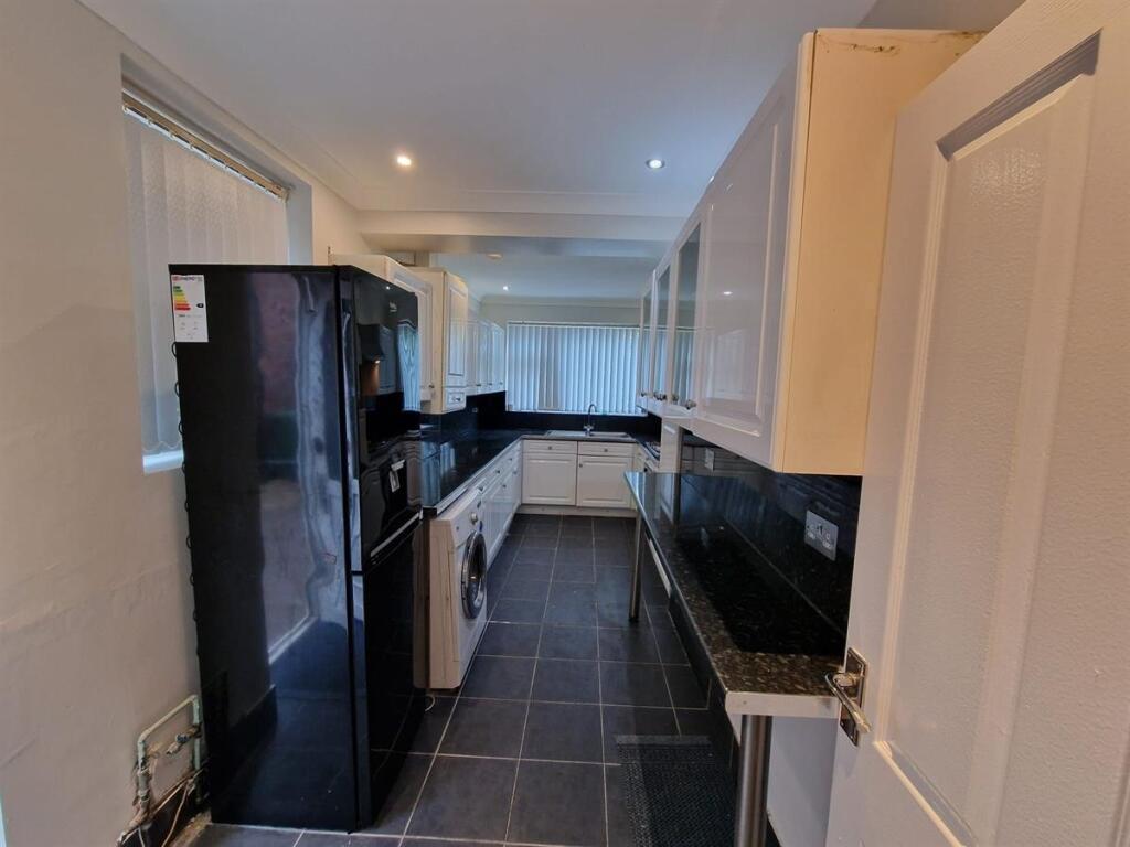 Modern galley kitchen with glossy black worktop...