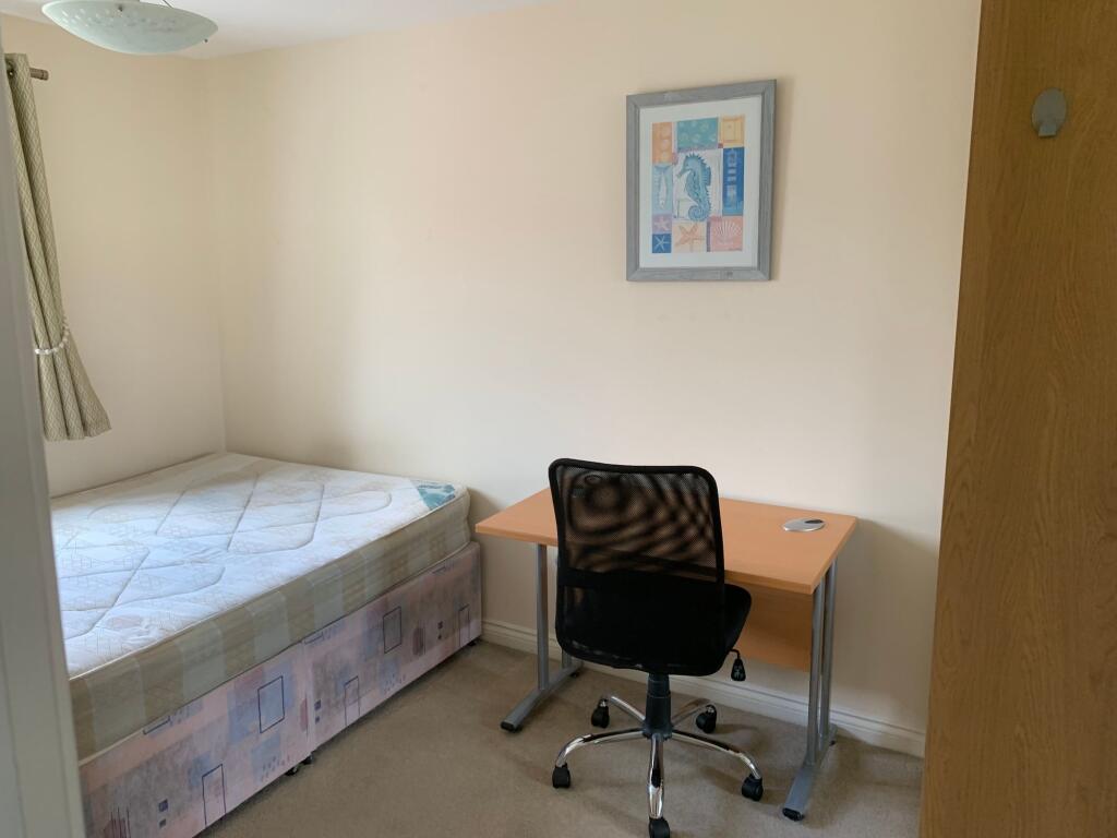 A cozy single bedroom featuring a neatly made b...