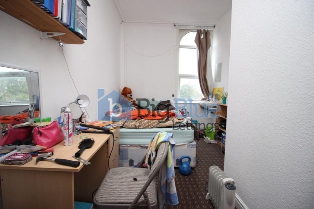 Cozy single bedroom featuring a desk with ample...