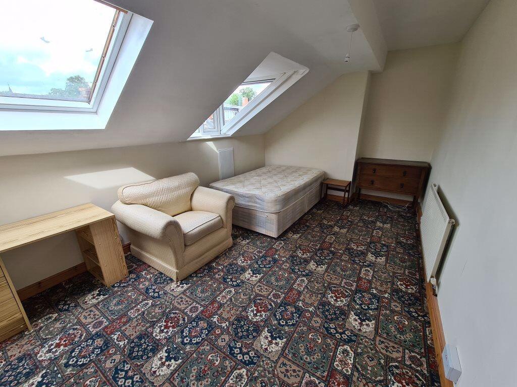 A cozy attic bedroom featuring a single bed, a ...