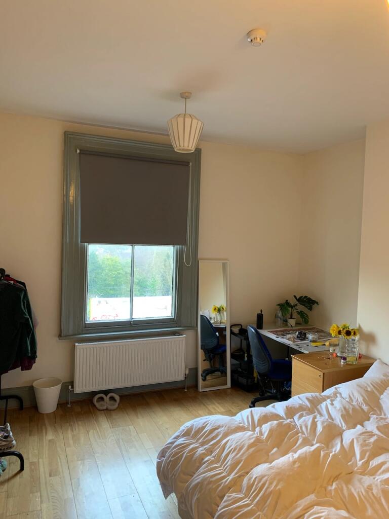 A cozy single bedroom with wooden flooring, a l...