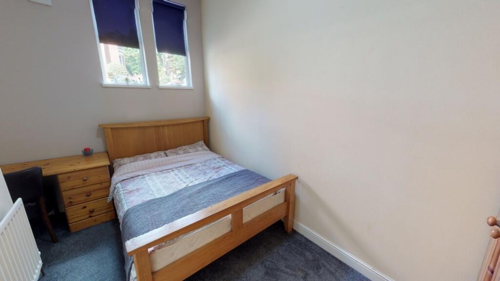 A cozy double bedroom featuring a wooden bed fr...