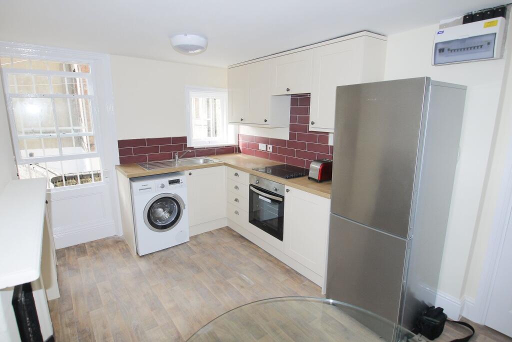Modern kitchen featuring cream cabinetry with c...