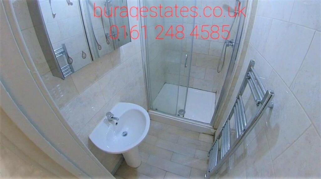 Clean modern bathroom with a glass-enclosed sho...