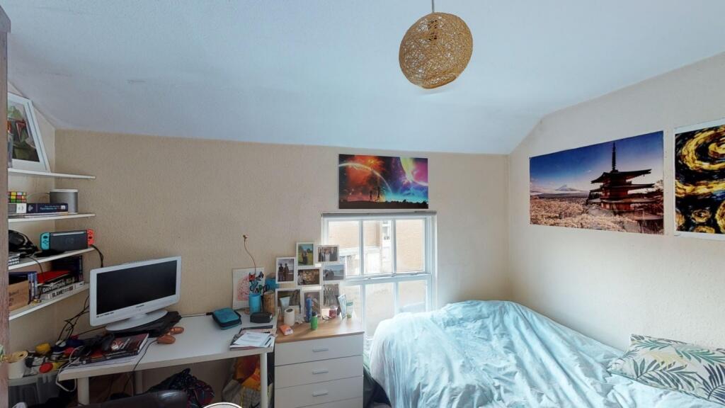 A cozy and well-lit single bedroom featuring a ...
