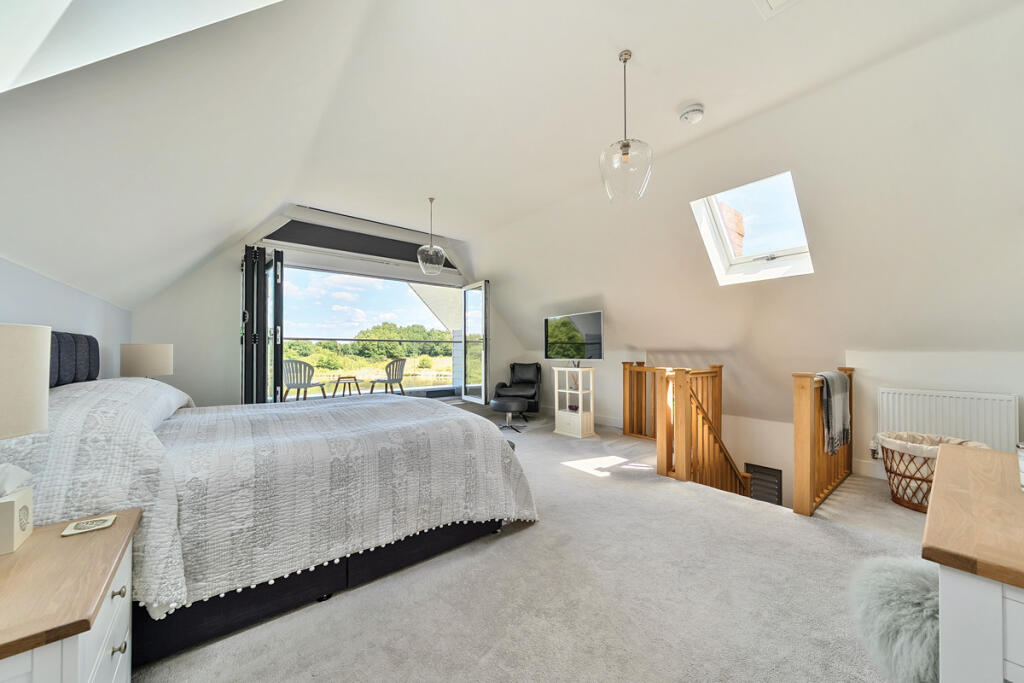 Master Bedroom with vaulted ceiling and bi-fold doors opening out onto balcony with stunning views over the lake