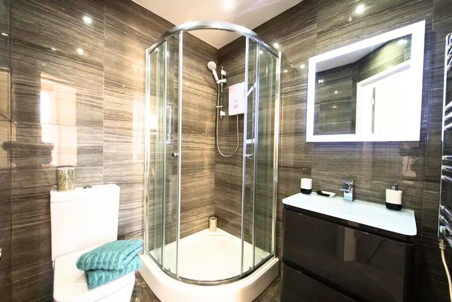 A modern bathroom featuring a sleek curved glas...