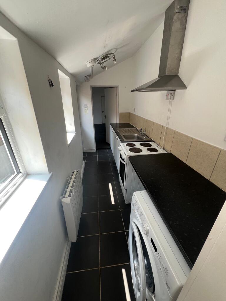 A narrow kitchen space featuring a washing mach...