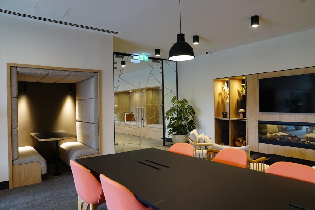 A modern communal workspace featuring a large b...