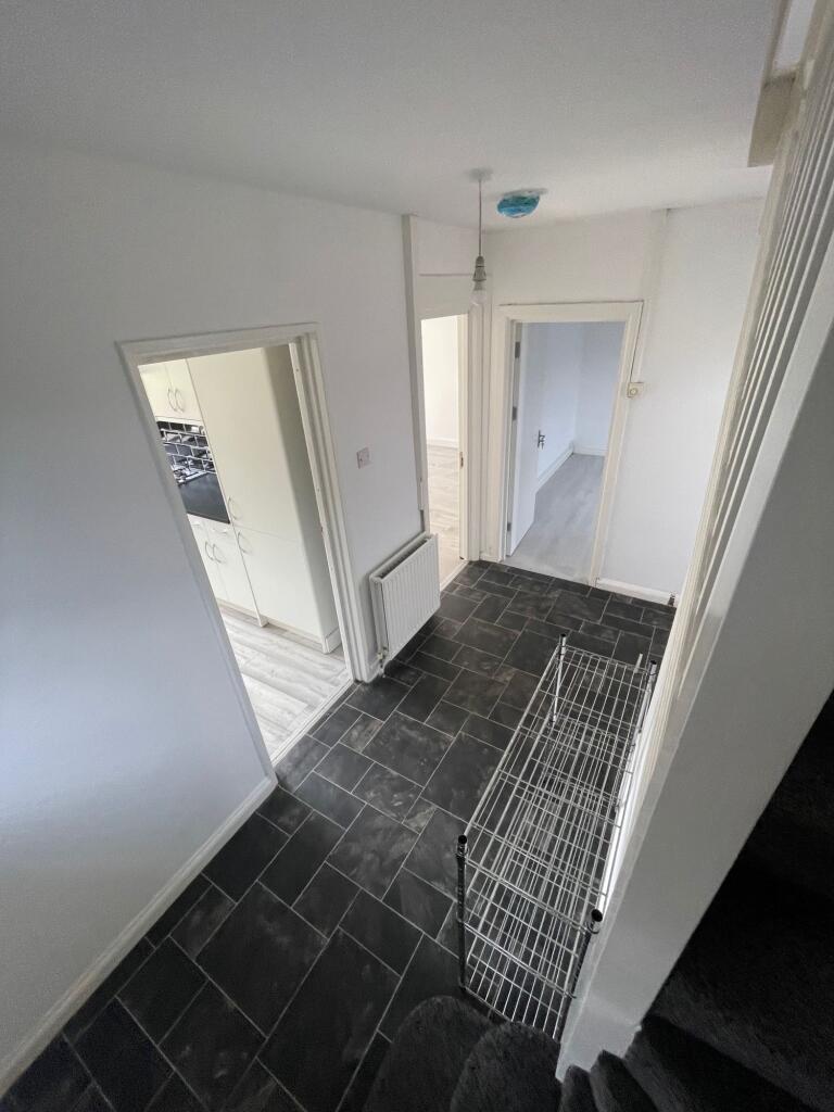 A clean and tidy hallway featuring dark tiled f...