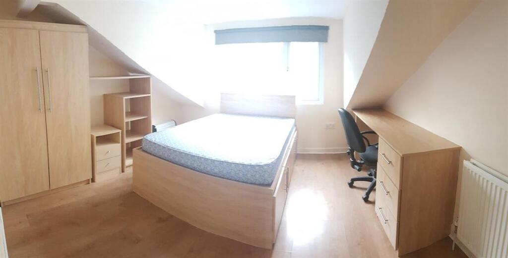 A bright and tidy bedroom featuring a comfortab...