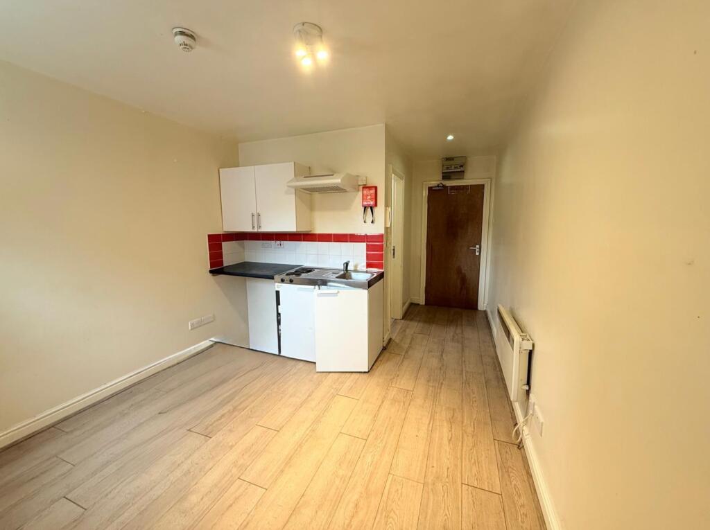 Compact kitchen area featuring modern white cab...