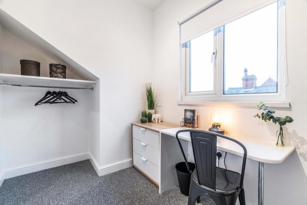 A bright and tidy bedroom featuring a large win...
