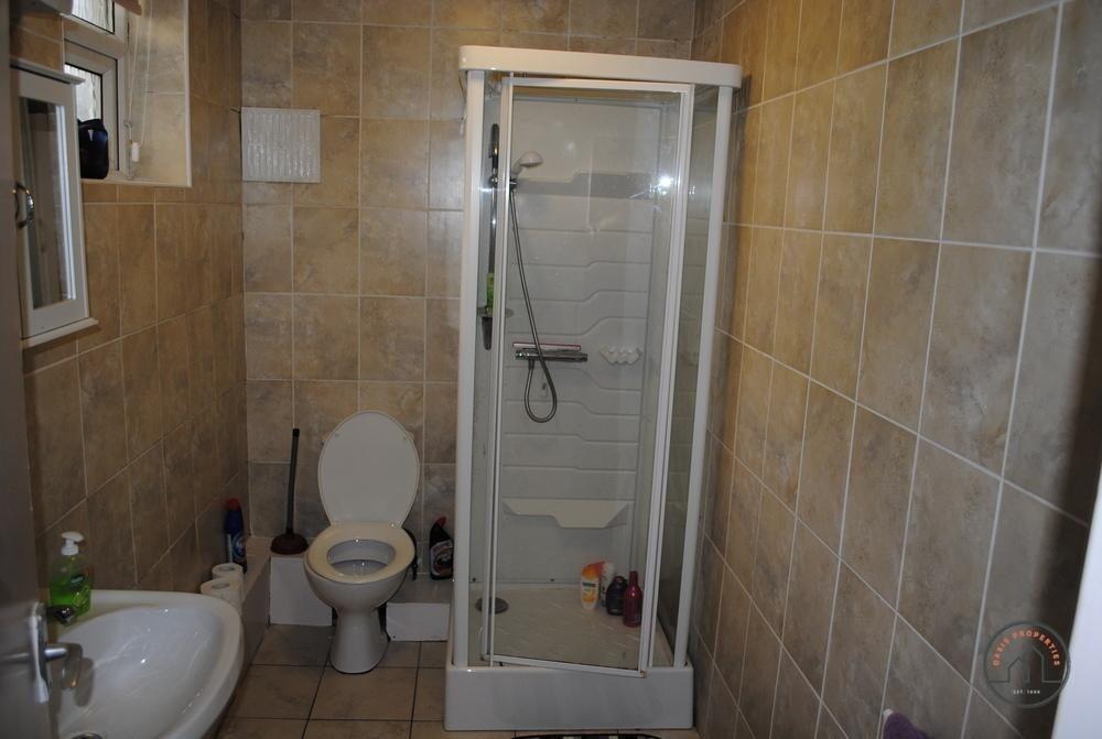 A clean bathroom featuring a toilet, small show...