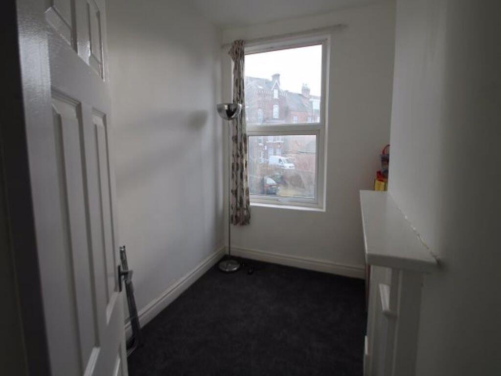 A small, simply furnished bedroom with a window...