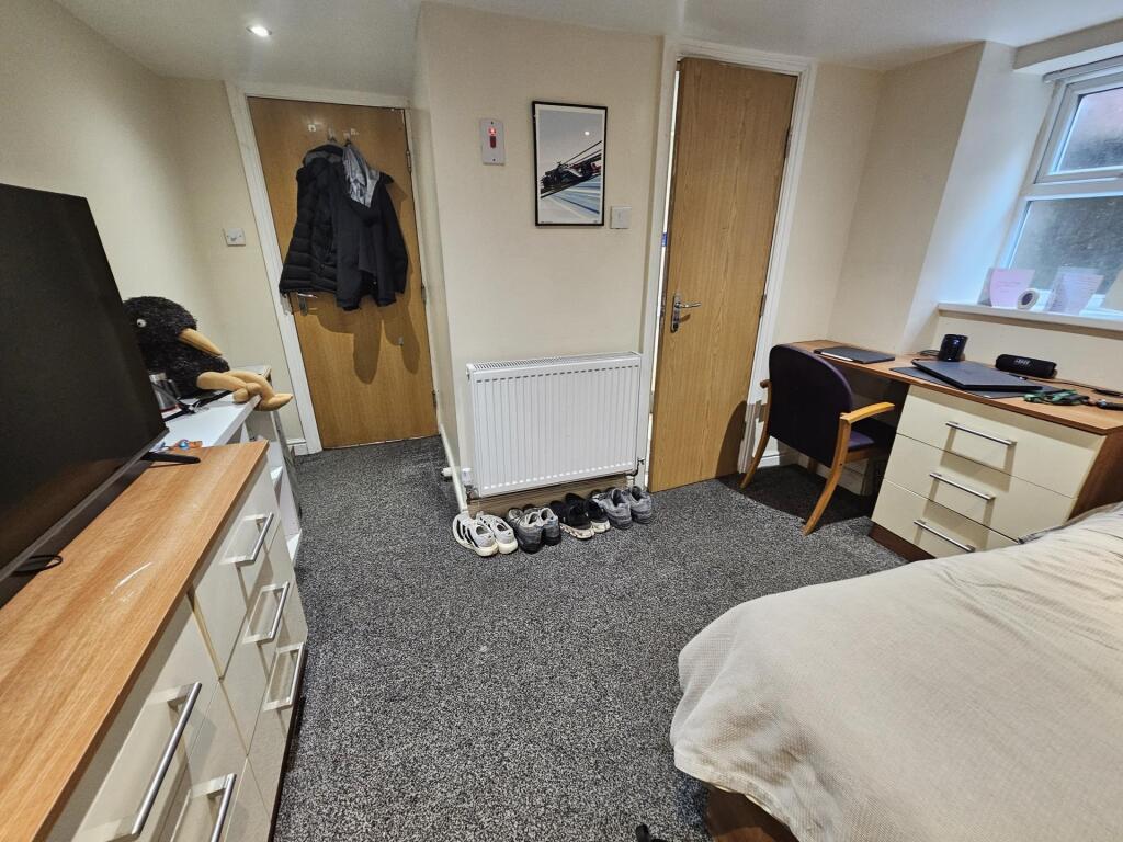 A cozy bedroom featuring a neatly made bed, a d...