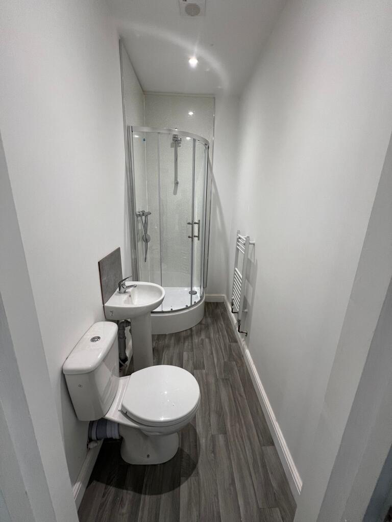 A modern bathroom featuring a curved glass show...