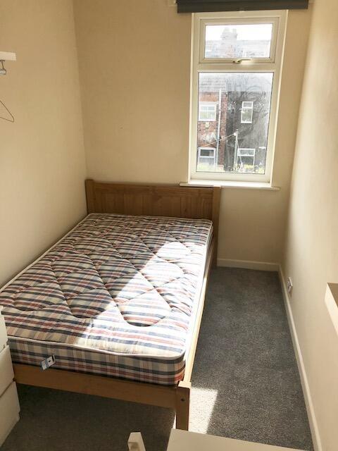 A cozy single bedroom featuring a wooden bed fr...