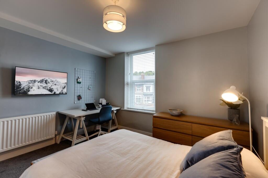 A cozy and well-lit bedroom featuring a comfort...