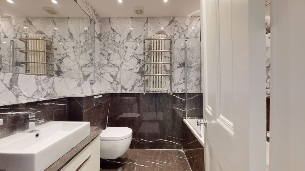 A sleek bathroom suite featuring elegant marble...
