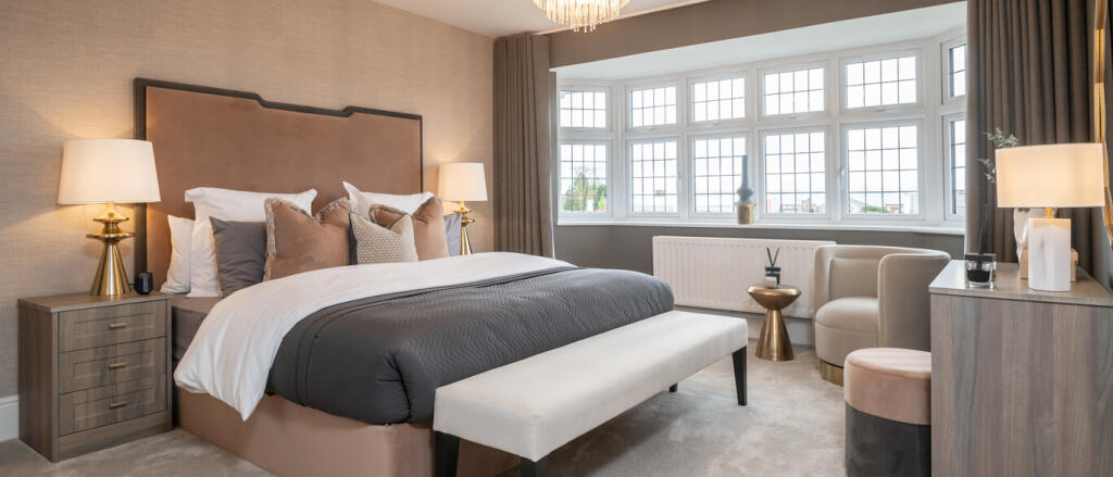 A modern, well-lit bedroom with a large bay window, plush bedding, beige and grey decor, and stylish