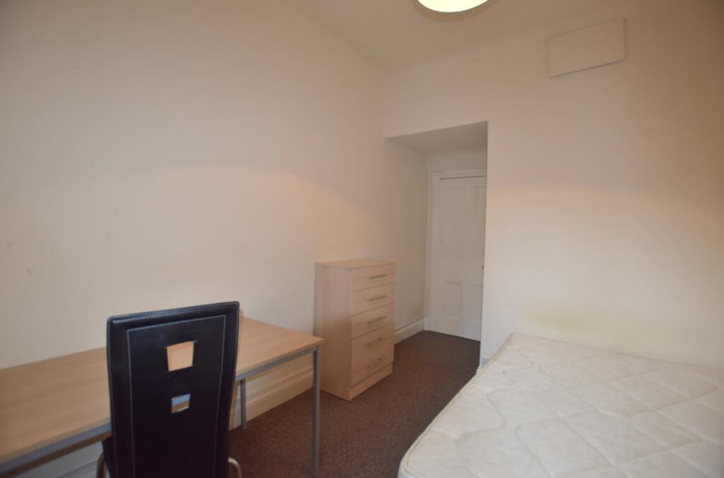 A spacious double bedroom featuring a desk and ...