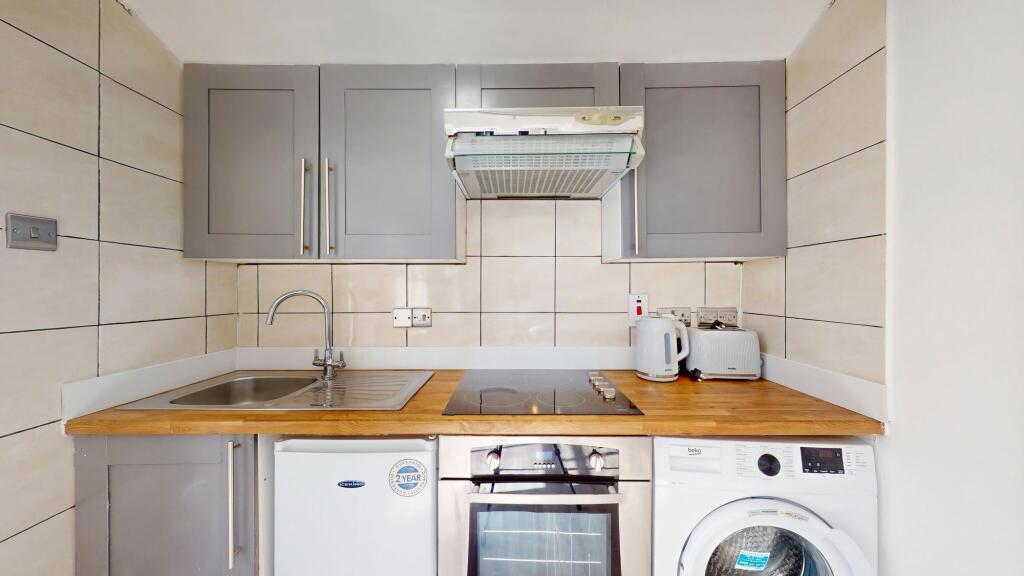 A modern kitchen featuring grey cabinets, a sma...