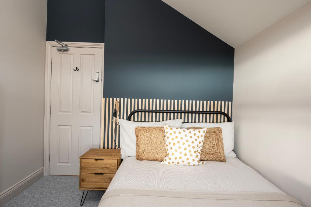 Bright, neatly styled bedroom with a metal bedf...