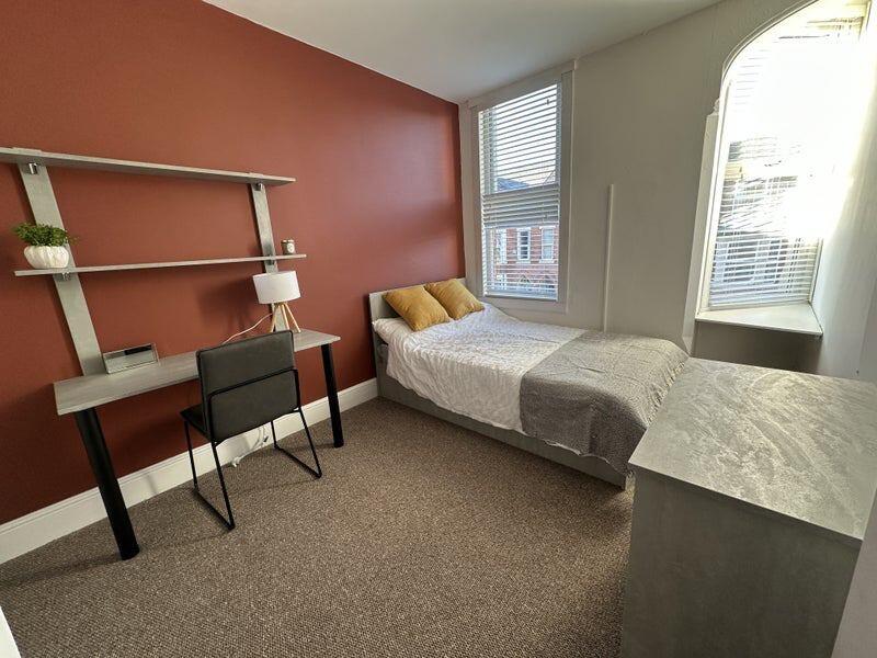 A bright and cozy single bedroom featuring warm...