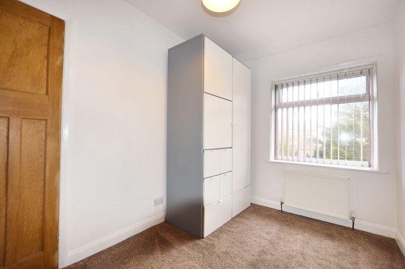 A tidy single bedroom with a large window allow...
