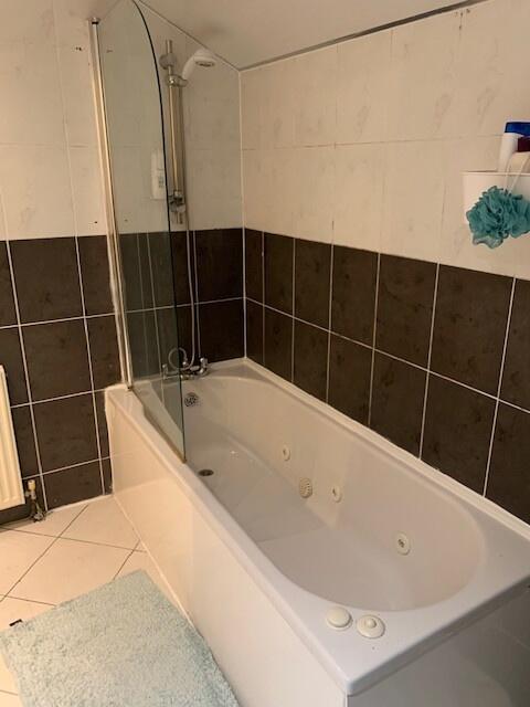 Modern tiled bathroom featuring a built-in whir...