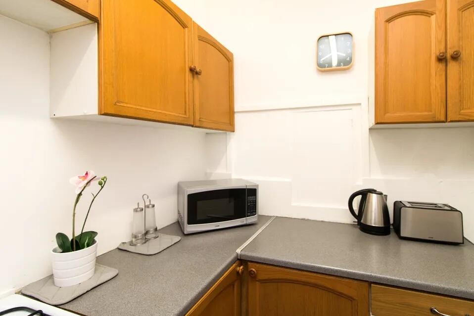Bright and tidy kitchen featuring wooden cabine...