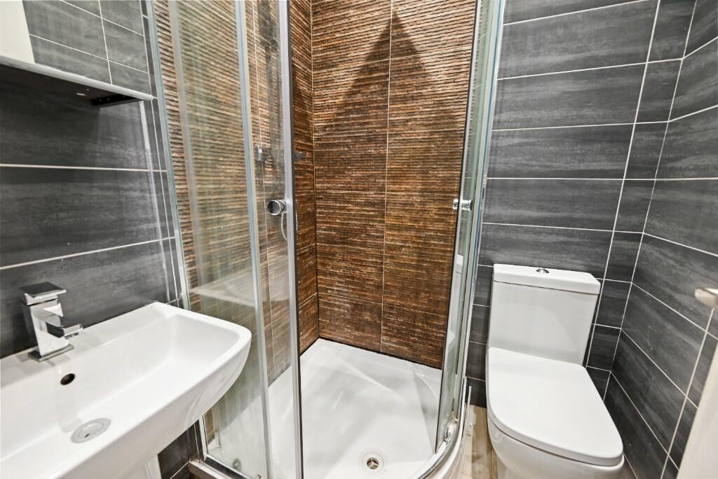 A modern bathroom suite featuring a glass-enclo...