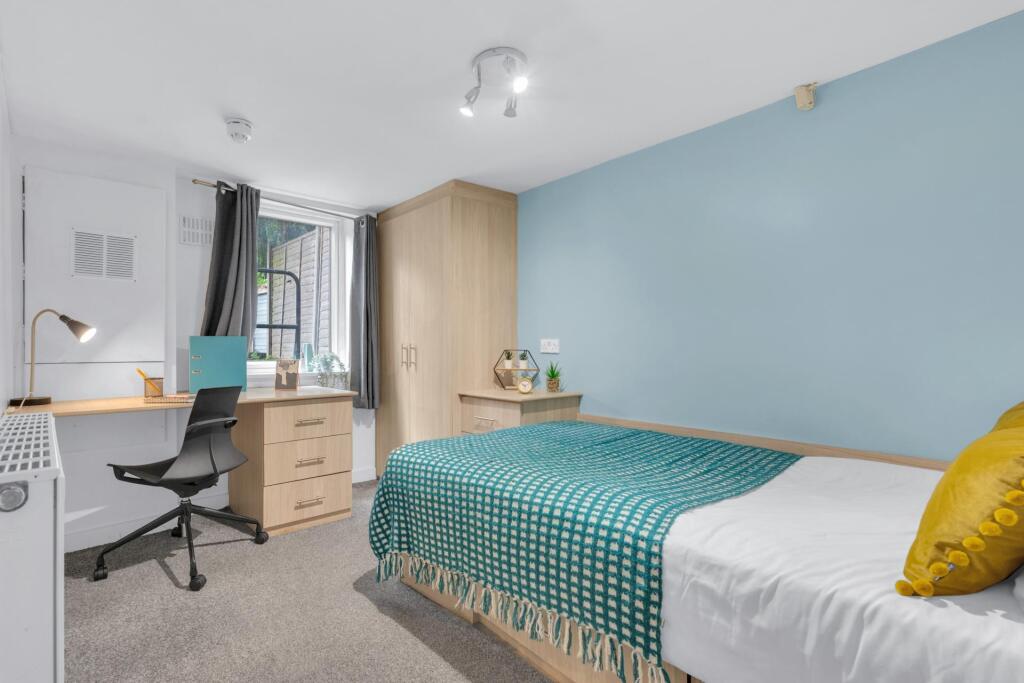 A neat and cozy single bedroom featuring a comf...