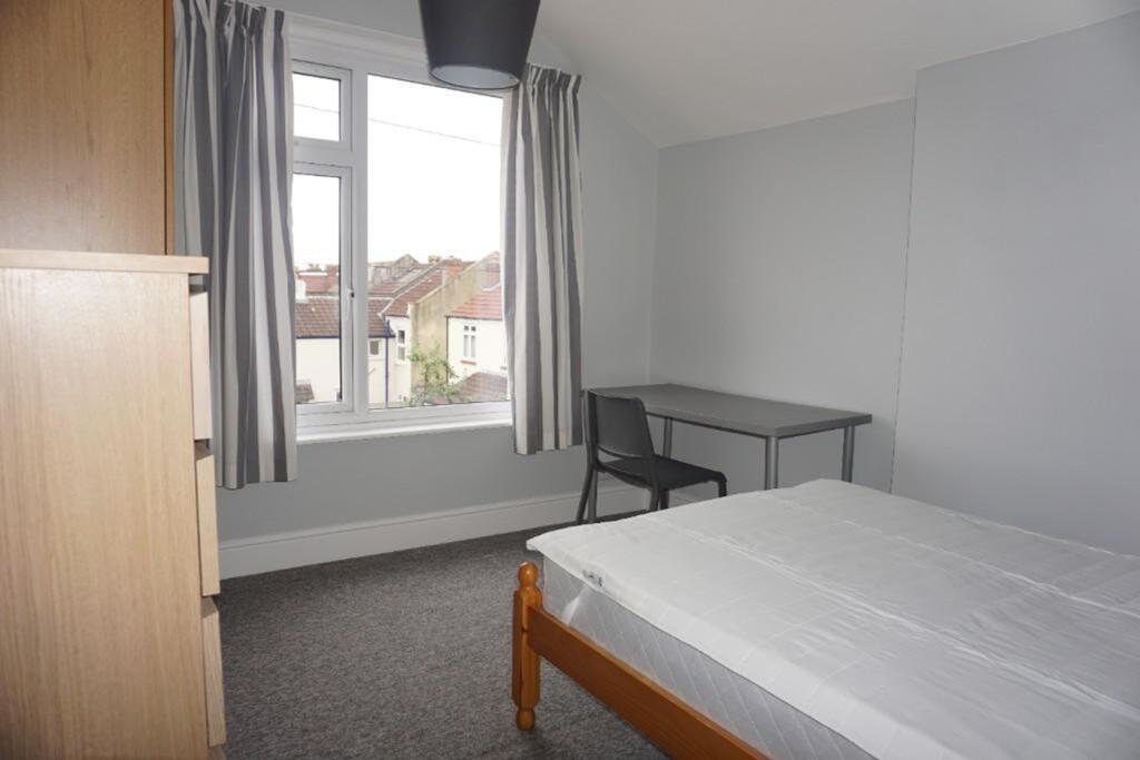A bright and tidy double bedroom with a desk an...