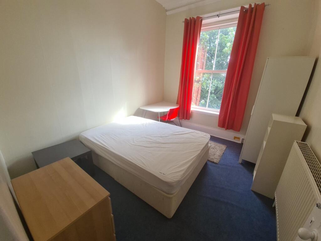 A bright and tidy bedroom featuring a comfortab...