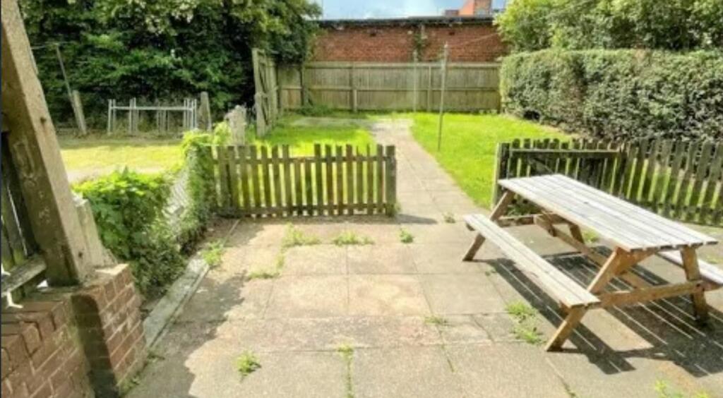 A sunlit garden featuring a wooden picnic bench...